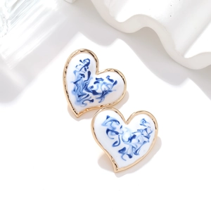 Elegant gold heart studs with blue enamel porcelain patterns on a white stone base