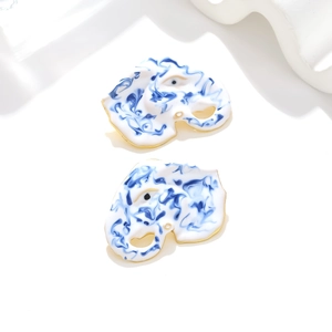 Detailed macro view of enamel elephant earrings with blue marble texture and gold plating