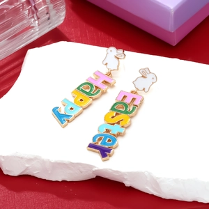 Macro shot of colorful enamel Happy Easter earrings with cute white bunny accents