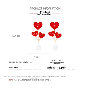 Macro view of heart balloon earrings with I Love You text and teardrop pearl drops