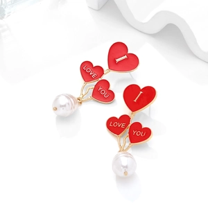 Close-up of red heart earrings with I LOVE YOU letters and pearl drops on a white base