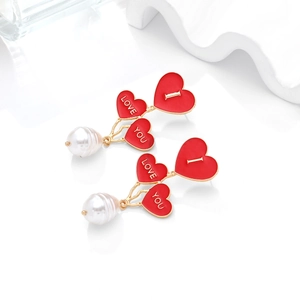 Detail of red enamel heart earrings with white I Love You letters and Baroque pearls