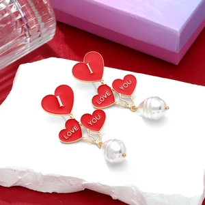 Detailed macro view of red enamel heart earrings with I Love You text and white pearls