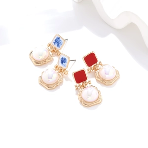 Close-up of handmade enamel pearl earrings with blue and red geometric vintage pendants