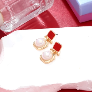Detail of red enamel square stud earrings with round pearl drops on a gold setting