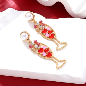 Champagne glass dangle earrings with pearls and heart patterns on red background