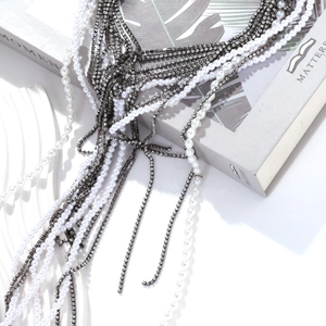 Collier multicouche avec perles blanches et chaînes en strass sur un livre gris