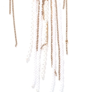 Détail de perles blanches et de franges en strass brillants sur un collier long doré