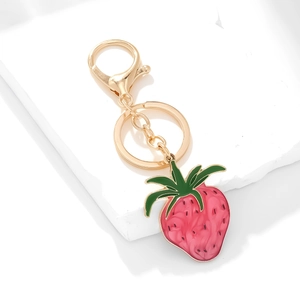 Cute gold strawberry keychain with pink enamel fruit and green leaf on stone stand