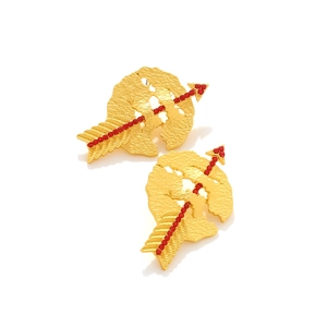 Macro detail of gold-plated cupid arrow earrings with red rhinestones and hammered texture