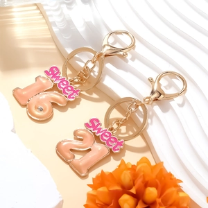 Close-up of pink drip oil Sweet 16 and 21 digital pendant keychains on gold metal chain