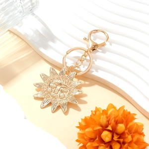 Golden celestial sun face pendant keychain with lobster clasp on a stylish display