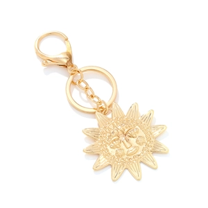 Golden alloy sunflower keychain with creative celestial sun face pendant on white background