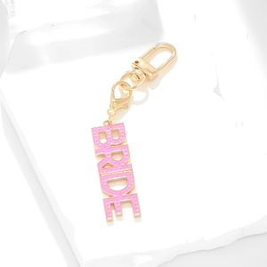 Golden BRIDE alphabet keychain with pink enamel charms on a white stone background