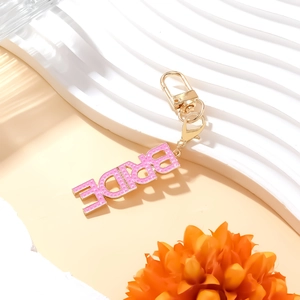 Pink enamel BRIDE letter keychain with gold base on a decorative white display stand