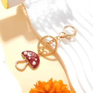 Red enamel mushroom keychain with white pearls and pink rhinestones on a gold ring