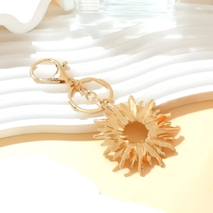 Chic golden alloy sun pendant keychain with sunflower motif and lobster clasp on white tray