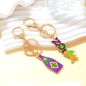 Détail des breloques NOLA et bouteille Mardi Gras en émail violet vert et jaune