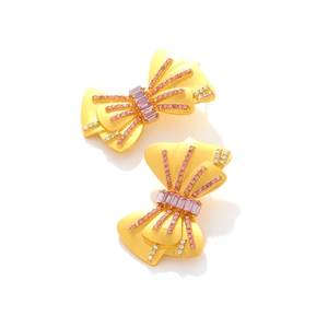 Boucles d'oreilles nœud papillon vintage dorées avec strass roses sur fond blanc