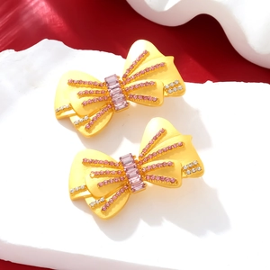 Détail de boucles d'oreilles nœud de luxe avec strass roses et blancs sur rouge