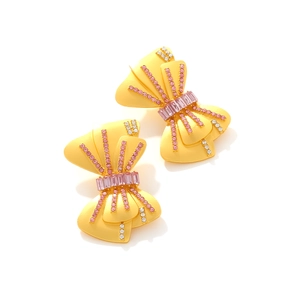 Boucles d'oreilles nœuds dorées avec strass roses et blancs sur fond blanc