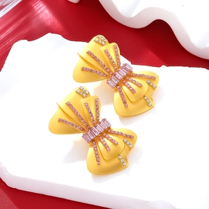 Boucles d'oreilles nœud vintage jaunes avec cristaux roses sur plateau en pierre