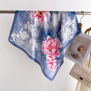 Detailed drape of blue floral silk scarf featuring pink peonies and stylish chain bag