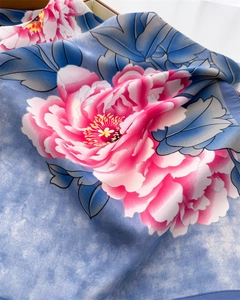 Close-up of silk scarf showing large pink peonies on light blue fabric with subtle shine