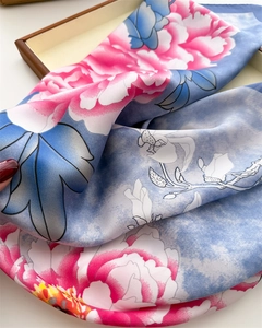 Detailed close-up of blue floral silk scarf with pink peonies on a wooden tray