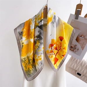 Elegant silk scarf featuring yellow ginkgo leaf patterns on a grey splash texture