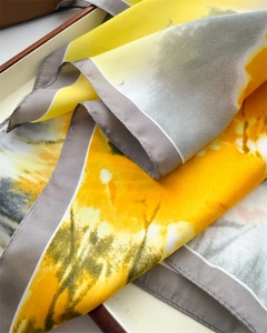 Detail of silk scarf with yellow and grey abstract ink print and rolled edges