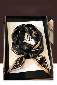 Detail of black satin scarf with gold leopard print on magazine prop in a gift box