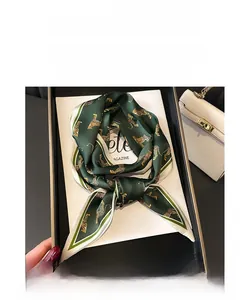 Macro detail of dark green leopard print silk scarf elegantly placed in a black gift box