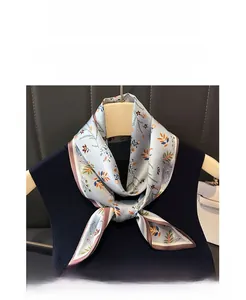 Détail du foulard en satin bleu clair à fleurs avec imprimé fin et bordure rose