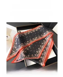 Détail d'un foulard étroit à motif cachemire avec texture satinée noire et orange