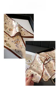 Gros plan d'un foulard élégant beige à fleurs orange avec bordure marron soignée