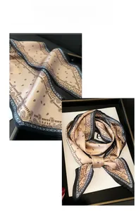 Détail macro de l'écharpe en soie paisley champagne doré avec bordure noire et nœud