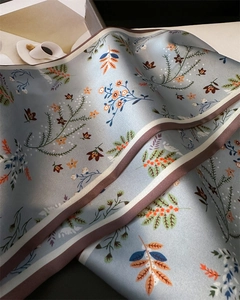 Gros plan du foulard en soie bleu clair avec motifs floraux et bordure rayée