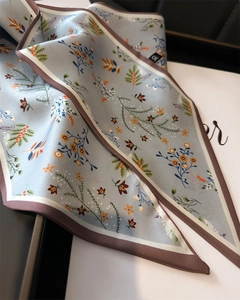 Vue détaillée d'une écharpe en soie bleu clair avec imprimé floral sur boîte