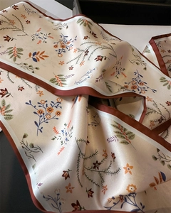 Gros plan sur un élégant foulard floral en satin avec des détails d'ourlet marron