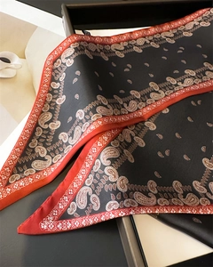 Détail d'un foulard en soie à motif paisley avec bords rouges et texture élégante