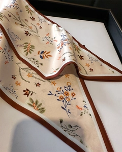 Gros plan détaillé d'un élégant foulard en soie avec des motifs floraux orange et verts