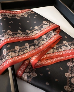 Gros plan d'un foulard en soie à motif cachemire noir avec bordure rouge