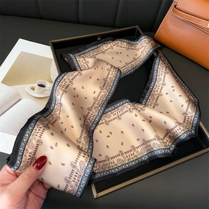 Gros plan du foulard en soie doré champagne avec motif paisley et bordure géométrique