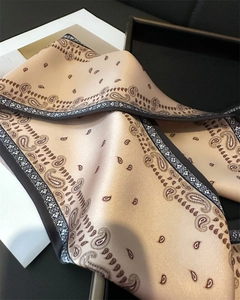 Détail d'un foulard en soie à motif paisley doré avec un drapé luxueux et bords contrastés