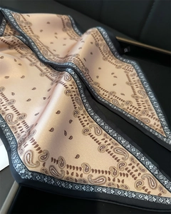 Vue détaillée du motif paisley sur écharpe en soie dorée champagne avec bords noirs
