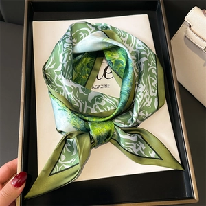Artistic green and white pattern silk scarf tied in a bow on a luxury display tray