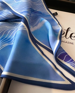 Detail of silk scarf showing blue wave pattern texture and premium hemmed edges