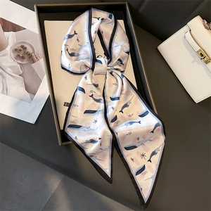 Detail of elegant whale print silk scarf tied in a bow next to a white handbag