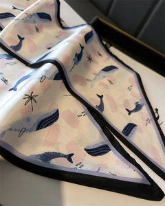 Detailed view of silk scarf with whale patterns, smooth texture, and black satin edges